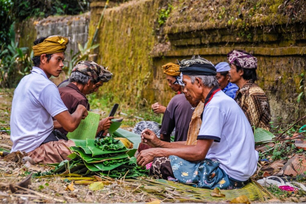 Balinese people working on ceremonial trinkets together as a part of a Banjar
