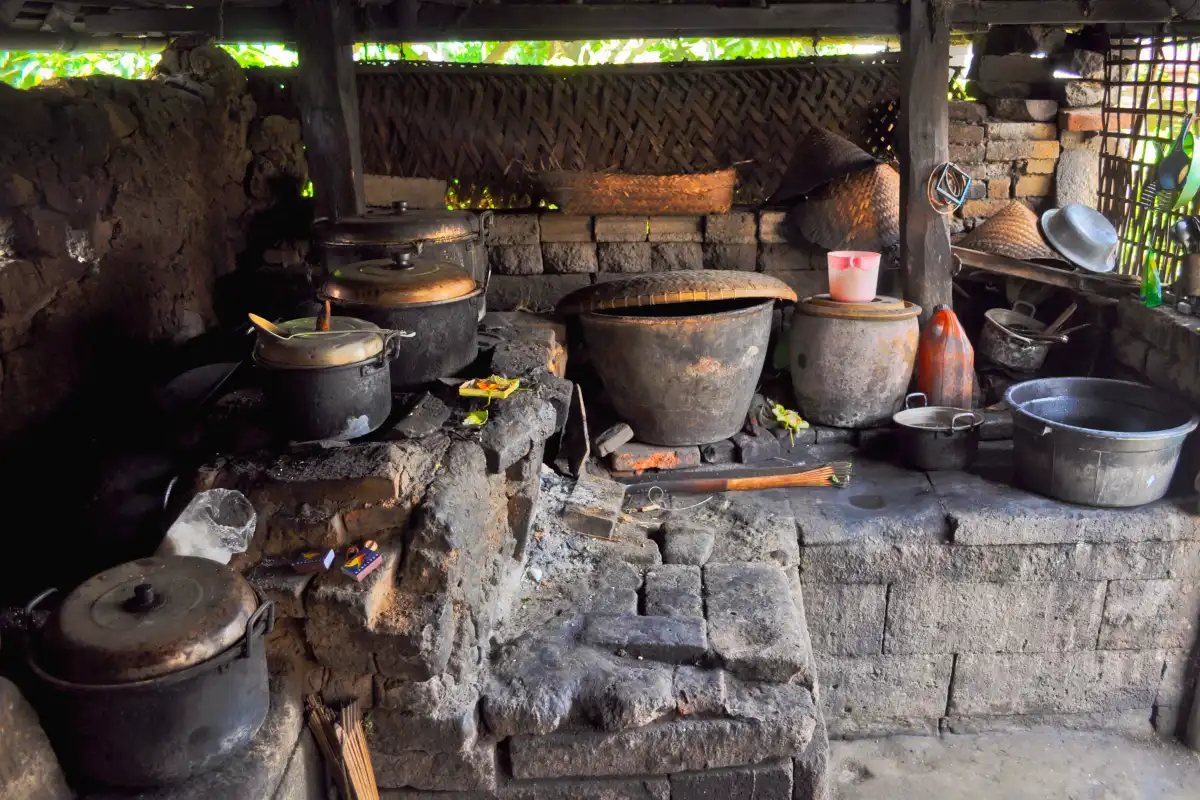 Traditional Balinese village kitchen with cooking utensils and woven rice basket