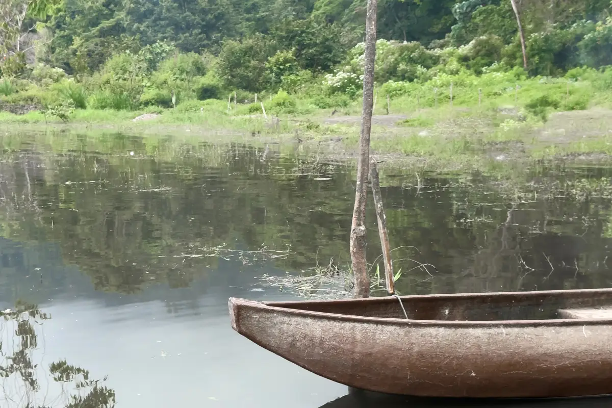 Traditional wooden canoe on Lake Tamblingan with forested hills behind