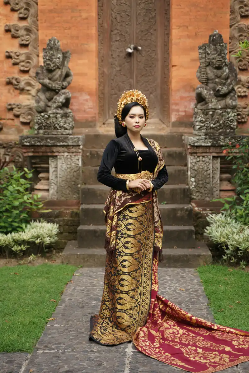Balinese woman wearing a traditional kebaya and woven cloth near a temple